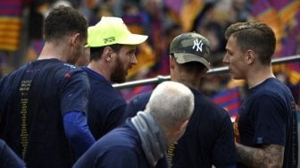 Pemain Barcelona Lionel Messi (topi kuning) berbincang dengan rekannya saat mengikuti parade kemenangan Los Cules [AFP]