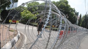 Pihak kepolisian memasang barikade kawat berduri di jalan Imam Bonjol, Jakarta, Selasa (1/5). 