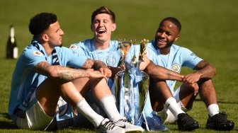 Tiga pemain Man City (kiri-kanan) Kyle Walker, John Stones dan Reheem Sterling bergembira setelah timnya dikukuhkan sebagai juara Liga Inggris 2017/18 usai laga kontra Huddersfield Town, Minggu (6/5/2018) di Etihad Stadium [AFP] 