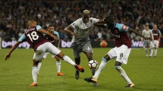 Gelandang Manchester United Paul Pogba (tengah) membawa bola mencoba melewati dua pemain West Ham United. Ian KINGTON / AFP