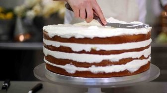 Pemilik Violet Bakery, Claire Ptak menyelesaikan kue untuk pernikahan Pangeran Harry dan Meghan Markle di dapur Istana Buckingham, London, Kamis (17/5).