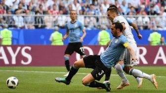 Pemain Rusia Denis Cheryshev dihadang kapten timnas Uruguay Diego Godin di pertandingan Grup A Piala Dunia 2018 yang digelar di Samara Arena, Senin (25/6/2018) [AFP]