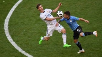 Pemain Rusia Aleksey Miranchuk (kiri) berebut bola dengan pemain Uruguay Lucas Torreira dalam pertandingan yang digelar di Samara Arena, Senin (25/6/2018) [AFP]