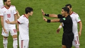 Penyerang Timnas Iran, Sardar Azmoun memprotes keras keputusan wasit asal Paraguay, Enrique Caceres di laga kontra Portugal (Mladen ANTONOV / AFP)