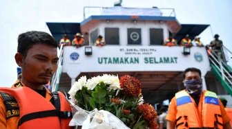 Anggota Basarnas memegang bunga saat berlangsung prosesi tabur bunga bagi korban tenggelamnya KM Sinar Bangun di kawasan titik tenggelamnya kapal di Danau Toba, Sumatera Utara, Senin (2/7). 