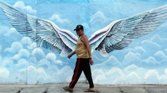 Sejumlah warga tampak melintas di samping beberapa lukisan mural tiga dimensi di kawasan Jatinegara, Jakarta, Jumat (6/7/2018). [Suara.com/Muhaimin A Untung]