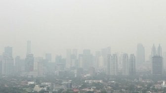 Pemandangan gedung-gedung bertingkat dan kawasan permukiman yang terhalang polusi udara di Jakarta, Jumat (13/7/2018). [Suara.com/Muhaimin A Untung]