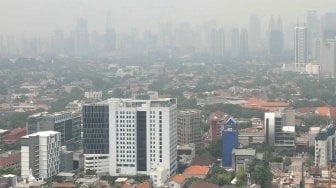 Pemandangan gedung-gedung bertingkat dan kawasan permukiman yang terhalang polusi udara di Jakarta, Jumat (13/7/2018). [Suara.com/Muhaimin A Untung]