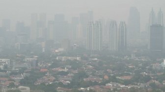 Pemandangan gedung-gedung bertingkat dan kawasan permukiman yang terhalang polusi udara di Jakarta, Jumat (13/7/2018). [Suara.com/Muhaimin A Untung]