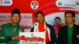 Atlet Indonesia juara dunia atletik nomor Lari 100 meter U-20 Lalu Muhammad Zohri (kanan) membentangkan Bendera Merah Putih setibanya dari Finlandia di Bandara Internasional Soekarno Hatta, Tangerang, Banten, Selasa (17/7). Lalu Muhammad Zohri menjadi Juara atletik nomor Lari 100 meter putra Kejuaraan Dunia IAAF U-20 2018 di Finlandia. ANTARA FOTO/Muhammad Iqbal