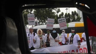 Ratusan orang yang tergabung dalam Pergerakan Dokter Muda Indonesia melakukan aksi di depan Taman Aspirasi Monas, Jakarta, Jumat (19/7). Dalam aksinya mereka meminta agar Kemeristekdi mengeluarkan ijazah Dokter yang disita.[suara.com/Muhaimin A Untung]