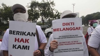 Ratusan orang yang tergabung dalam Pergerakan Dokter Muda Indonesia melakukan aksi di depan Taman Aspirasi Monas, Jakarta, Jumat (19/7). Dalam aksinya mereka meminta agar Kemeristekdi mengeluarkan ijazah Dokter yang disita.[suara.com/Muhaimin A Untung]
