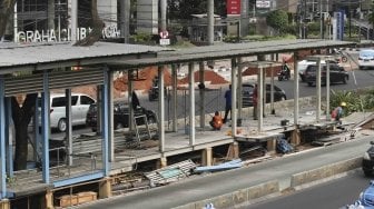 Sejumlah pekerja terlihat menyelesaikan pembangunan perluasan halte Transjakarta Gelora Bung Karno (GBK) di Jalan Sudirman, Jakarta, Jumat (20/7/2018). [Suara.com/Muhaimin A Untung]