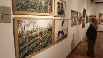 Pengunjung memperhatikan foto yang dipamerkan di Festival Kopi di Bentara Budaya, Jakarta, Minggu (22/7). [suara.com/MuhaiminA Untung]