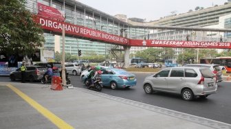 Sejumlah kendaraan melintasi Jembatan Penyebrangan Orang (JPO) di Bundaran HI, Jakarta, Rabu (25/7). Gubernur DKI Jakarta Anies Baswedan berencana akan melakukan pembongkaran JPO Bundaran HI agar tidak menganggu patung selamat datang yang dibangun untuk menyambut peserta Asian Games. Nantinya usai dirobohkan, dilokasi tersebut akan dibangun 'Pelican Crossing' untuk memudahkan pejalan kaki menyeberang jalan. [suara.com/Oke Dwi Atmaja]