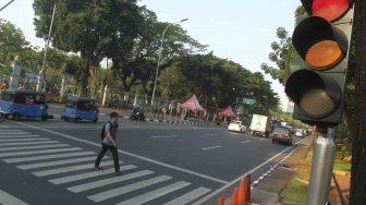 Warga menyebrang melalui Pelican Crosing di kawasan Merdeka Barat, Jakarta, Sabtu (28/7). Pemprov DKI Jakarta segera membuat pelican crossing sebagai pengganti jembatan penyeberangan orang (JPO) di Bundaran HI yang akan dirobohkan dengan alasan keindahan dan tak ramah difabel. [suara.com/Muhaimin A Untung]