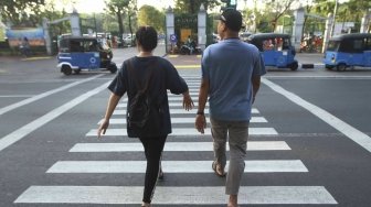 Warga menyebrang melalui Pelican Crosing di kawasan Merdeka Barat, Jakarta, Sabtu (28/7). Pemprov DKI Jakarta segera membuat pelican crossing sebagai pengganti jembatan penyeberangan orang (JPO) di Bundaran HI yang akan dirobohkan dengan alasan keindahan dan tak ramah difabel. [suara.com/Muhaimin A Untung]