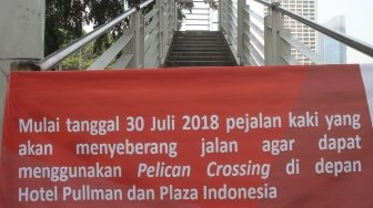 Kendaraan melintasi Jembatan Penyeberangan Orang (JPO) Bunderan Hotel Indonesia, Jakarta, Senin (30/7). Jembatan penyeberangan orang di kawasan Bundara Hotel Indonesia, hari ini ditutup dan akan dibongkar sehingga tak bisa dipakai lagi. Sebagai gantinya, pejalan kaki bisa menggunakan pelican crossing yang sudah dibuat sebagai tempat penyeberangan sementara.[Suara.com/Oke Dwi Atmaja].