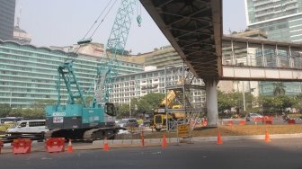 Kendaraan melintasi Jembatan Penyeberangan Orang (JPO) Bunderan Hotel Indonesia, Jakarta, Senin (30/7). Jembatan penyeberangan orang di kawasan Bundara Hotel Indonesia, hari ini ditutup dan akan dibongkar sehingga tak bisa dipakai lagi. Sebagai gantinya, pejalan kaki bisa menggunakan pelican crossing yang sudah dibuat sebagai tempat penyeberangan sementara.[Suara.com/Oke Dwi Atmaja].