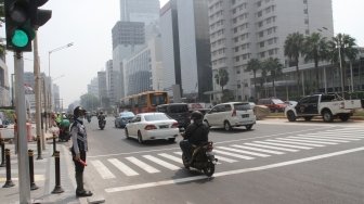 Pejalan kaki sedang menyebrang di pelican crossing dikawasan Thamrin, Jakarta, Senin (30/7). Pelican crossing dikawasan Thamrin sudah bisa di gunakan sebagai pengganti JPO yang akan dibongkar. [Suara.com/Oke Dwi Atmaja]