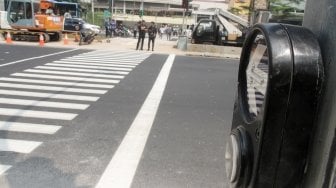 Pejalan kaki sedang menyebrang di pelican crossing dikawasan Thamrin, Jakarta, Senin (30/7). Pelican crossing dikawasan Thamrin sudah bisa di gunakan sebagai pengganti JPO yang akan dibongkar. [Suara.com/Oke Dwi Atmaja]