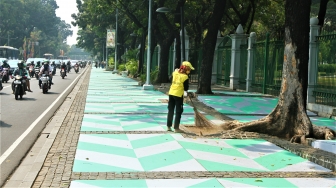 Warga melintas di Trotoar kawasan Monumen Nasional yang sudah di cat, Jakarta, Selasa (31/7). Pengecatan trotoar atau fasilitas pejalan kaki ini untuk mempercantik kawasan silang Monas dalam menyambut pagelaran Asian Games 2018 yang akan berlangsung Agustus hingga September 2018 mendatang.[suara.com/Muhaimin A Untung]