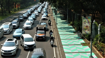 Warga melintas di Trotoar kawasan Monumen Nasional yang sudah di cat, Jakarta, Selasa (31/7). Pengecatan trotoar atau fasilitas pejalan kaki ini untuk mempercantik kawasan silang Monas dalam menyambut pagelaran Asian Games 2018 yang akan berlangsung Agustus hingga September 2018 mendatang.[suara.com/Muhaimin A Untung]