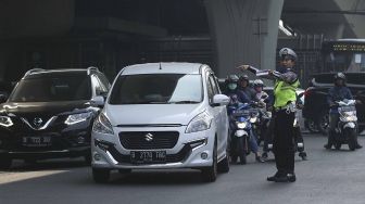 Polisi memberhentikan mobil berplat genap yang melintas pada tanggal ganjil di kawasan pancoran, Jl MT Haryono, Jakarta, Rabu (1/8). Aturan sistem perluasan lalu lintas ganjil-genap di sejumlah ruas jalan protokol Jakarta jelang asian games diberlakukan penilangan per tanggal 1 Agustus, bagi pengendara yang melanggar akan dikenai sanksi sebesar Rp 500 ribu.[suara.com/Muhaimin A Untung]