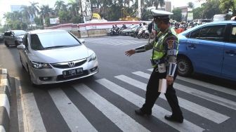 Polisi memberhentikan mobil berplat genap yang melintas pada tanggal ganjil di kawasan pancoran, Jl MT Haryono, Jakarta, Rabu (1/8). Aturan sistem perluasan lalu lintas ganjil-genap di sejumlah ruas jalan protokol Jakarta jelang asian games diberlakukan penilangan per tanggal 1 Agustus, bagi pengendara yang melanggar akan dikenai sanksi sebesar Rp 500 ribu.[suara.com/Muhaimin A Untung]