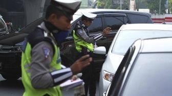 Polisi memberhentikan mobil berplat genap yang melintas pada tanggal ganjil di kawasan pancoran, Jl MT Haryono, Jakarta, Rabu (1/8). Aturan sistem perluasan lalu lintas ganjil-genap di sejumlah ruas jalan protokol Jakarta jelang asian games diberlakukan penilangan per tanggal 1 Agustus, bagi pengendara yang melanggar akan dikenai sanksi sebesar Rp 500 ribu.[suara.com/Muhaimin A Untung]