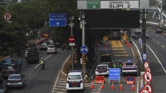 Dirlantas Polda Metro Jaya bersama Dinas Perhubungan DKI Jakarta menjaga pintu gerbang tol yang ditutup di Tol Slipi 2, Jakarta, Rabu (1/8). Penutupan pintu tol secara permanen di 19 pintu tol tersebut demi kelancaran transportasi penyelenggaraan Asian Games 2018 agar waktu tempuh perjalanan atlet dari wisma atlet menuju veneu cuma 30 menit. [suara.com/Muhaimin A Untung].