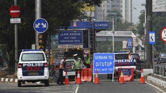 Dirlantas Polda Metro Jaya bersama Dinas Perhubungan DKI Jakarta menjaga pintu gerbang tol yang ditutup di Tol Slipi 2, Jakarta, Rabu (1/8). Penutupan pintu tol secara permanen di 19 pintu tol tersebut demi kelancaran transportasi penyelenggaraan Asian Games 2018 agar waktu tempuh perjalanan atlet dari wisma atlet menuju veneu cuma 30 menit. [suara.com/Muhaimin A Untung].