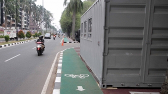 Kendaraan melintas di samping kontainer penjualan tiket Asian Games 2018 yang berada di trotoar Jalan Pintu Satu Senayan, kawasan Gelora Bung Karno (GBK), Jakarta, Rabu (8/8). [Suara.com/Oke Atmaja]