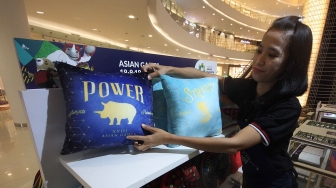 Sales promotion girl (SPG) merapikan bantal Asian Games di booth merchandise Asian Games 2018 di Senayan City, Jakarta,  Rabu (8/8). Penjualan merchandise dengan harga Rp10.000 sampai Rp4.000.000 itu dapat menyukseskan perhelatan Asian Games 2018. [Suara.com/Oke Atmaja]