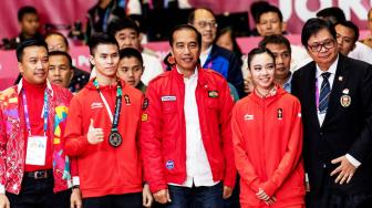 Presiden Joko Widodo (Jokowi) didampingi Menpora Imam Nahrawi dan Ketua Umum PB Wushu Indonesia, Airlangga Hartarto (kanan), berfoto bersama atlet wushu putri peraih medali emas Lindswell Kwok dan atlet wushu putra peraih medali perak Edgar Xavier Marvelo (kedua kiri), di sela-sela pertandingan wushu Asian Games 2018 di JIExpo, Kemayoran, Jakarta, Senin (20/8/2018). [Antara/INASGOC/Ismar Patrizki]