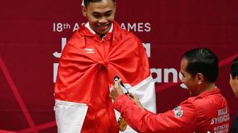 Presiden Joko Widodo (kanan) siap mengalungkan medali emas kepada lifter Indonesia Eko Yuli Irawan usai pertandingan nomor angkat besi putra 62 kg Group A, Asian Games ke-18 2018 di JiExpo, Jakarta, Selasa (21/8). ANTARA FOTO/INASGOC/Fanny Octavianus