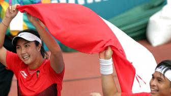 Petenis Indonesia Christopher Benjamin Rungkat (kanan) yang berpasangan dengan Aldila Sutjiadi (kiri) membawa bendera setelah menjadi juara dengan mengalahkan lawannya petenis Thailand Luksika Kumkhum dan Sonchat Ratiwatana pada babak final tenis ganda campuran Asian Games 2018 di JSC Tennis Courts, Palembang, Sumatera Selatan, Sabtu (25/8). ANTARA FOTO/INASGOC/Hendra Syamhari