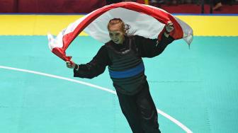 Ekspresi pesilat Indonesia Wewey Wita membawa bendera merah putih usai mengalahkan pesilat Vietnam Thi Them Tran (kanan) dalam babak final Kelas B Putri Asian Games 2018 di Padepokan Pencak Silat Taman Mini Indonesia Indah (TMII), Jakarta, Rabu (29/8). ANTARA FOTO/INASGOC/Melvinas Priananda