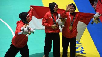 Tim silat Indonesia peraih medali emas Pramudita Yuristya (kiri), Lutfi Nurhasanah (tengah) dan Gina Tri Lestari (kanan) berpose usai upacara penyerahan medali nomor beregu putri pencak silat seni Asian Games 2018 di Padepokan Pencak Silat Taman Mini Indonesia Indah (TMII), Jakarta, Rabu (29/8). ANTARA FOTO/INASGOC/Melvinas Priananda