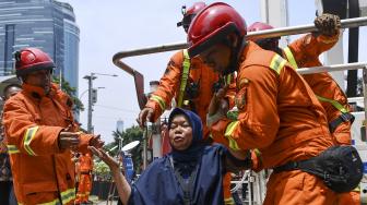 Petugas pemadam kebakaran mengevakuasi korban saat simulasi penanggulangan kebakaran di gedung KPK, Jakarta, Jumat (14/9).[ANTARA FOTO/Sigid Kurniawan]
