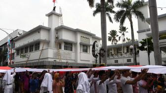 Peserta teatrikal membentangkan bendera Merah Putih saat memperingati peristiwa perobekan bendera di Hotel Yamato sekarang Hotel Majapahit di Jalan Tunjungan, Surabaya, Jawa Timur, Rabu (19/9). ANTARA FOTO/Zabur Karuru