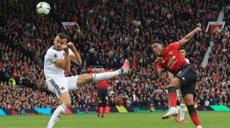 Striker Manchester United Anthony Martial menendang bola dan melewati gelandang asal Wolverhampton Wanderers, Romain Saiss, saat Manchester United melawan Wolverhampton Wanderers di Old Trafford di Manchester, Inggris, Sabtu (22/9). [AFP/Lindsey PARNABY]