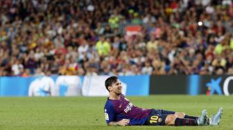 Lionel Messi duduk di lapangan selama pertandingan Barcelona melawan Girona di stadion Camp Nou,Barcelona, Minggu (23/9). [AFP/Pau Barrena] 
