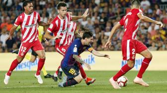 Lionel Messi terjatuh usai dihadang oleh para pemain Girono saat pertandingan Barcelona melawan Girona di Stadion Camp Nou, Barcelona, Spanyol, Minggu (23/9). [AFP/ Pau Barrena]
