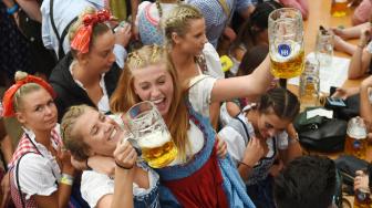 Para peserta mengangkat gelas bir saat pembukaan festival bir terbesar di dunia Oktoberfest ke-185 di Munich, Jerman, Sabtu (22/9). [AFP/Christof STACHE]
