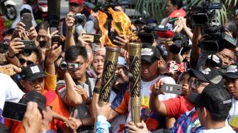 Suasana pawai obor Asian Para Games 2018 ketika melintas di kawasan Jalan Medan Merdeka Selatan, Jakarta, Minggu (30/9). [Suara.com/Oke Dwi Atmaja]