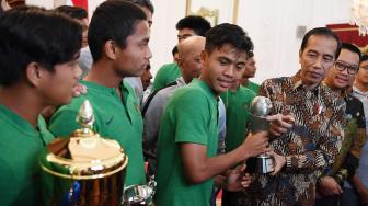 Presiden Joko Widodo (kedua kanan) didampingi Menpora Imam Nahrawi (kanan) memegang piala bersama pemain Timnas U-16 di Istana Merdeka, Jakarta, Kamis (4/10). [ANTARA FOTO/Wahyu Putro]