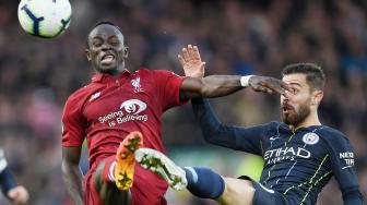 Striker Liverpool Sadio Mane bersaing memperebutkan bola dengan gelandang Manchester City Bernardo Silva selama pertandingan sepak bola Liga Inggris antara Liverpool melawan Manchester City di Stadion Anfield, Liverpool, Inggris, Minggu (7/10). [AFP/Paul ELLIS]