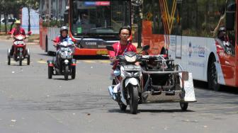 Driver Ojek disabilitas melintas di Kompleks Gelora Bung Karno,Senayan,Jakarta Pusat (8/10). [Suara.com/Fakhri Hermansyah]
