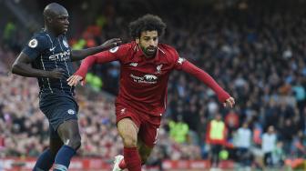 Striker Liverpool Mohamed Salah melewati pemain belakang Manchester City Benjamin Mendy selama pertandingan sepak bola Liga Primer Inggris antara Liverpool melawan Manchester City di Stadion Anfield, Liverpool, Inggris, Minggu (7/10).  [AFP/Paul ELLIS]